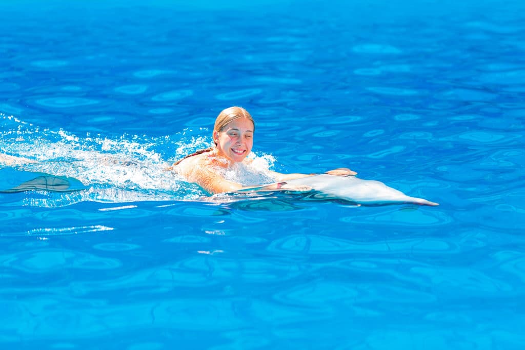 Happy little girl swimming with dolphins by Krystal International Vacation Club